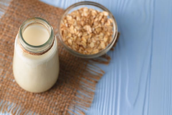 Vegan oat milk with oat flakes close up